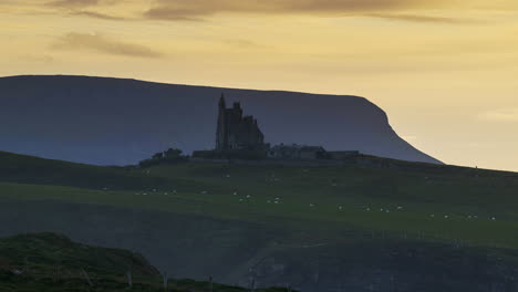 lapso de tiempo del castillo de classiebawn en la costa de pastizales con nubes de atardecer en movimiento en la cabeza de mullaghmore en el condado de sligo en el camino atlántico salvaje en irlanda