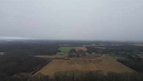 An-aerial-shot-of-farmland-in-the-middle-of-the-country-with-a-thick-heavy-fog-rolling-in