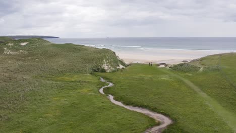 ascending drone shot of eoropie beach in ness with people walking on a sunny, summer's day