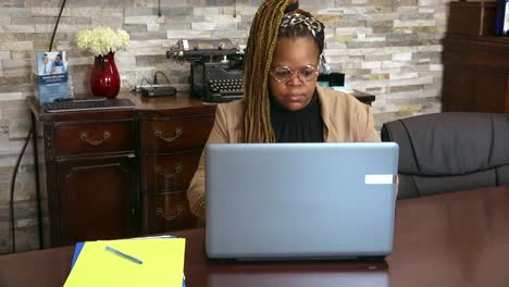 Black-business-owner-wearing-glasses-working-on-computer-in-conference-room