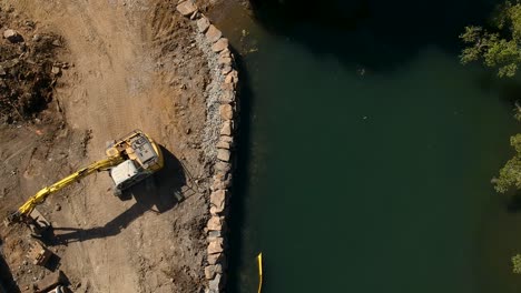 equipo de movimiento de tierra reparando una sección del río dañada por una inundación causada por un ciclón tropical