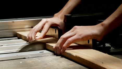 Female-welder-using-table-saw-on-a-wooden-plank-in-workshop-4k