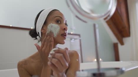 Mixed-race-woman-taking-a-bath-applying-beauty-face-mask