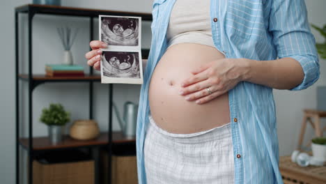 pregnant woman holding ultrasound photos
