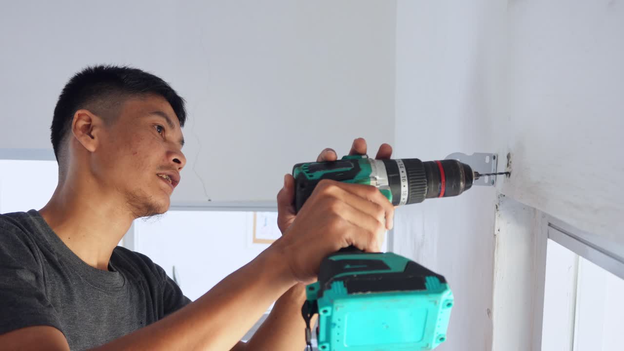 Determined handyman uses power drill for home improvements and DIY projects with precision