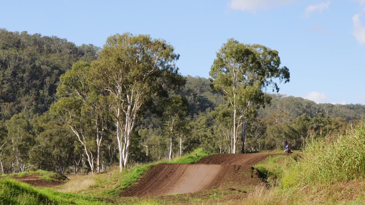 un motociclista navegando por una pista de tierra en un bosque exuberante