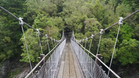 walking over suspension bridge at hokitika gorge, new zealand