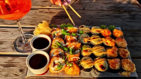 Hand reaches with chopsticks to grab sushi from plate, woman dining in soft lighting