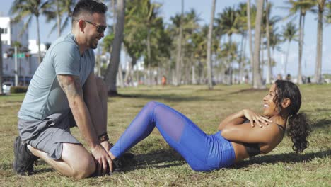 hombre apoyando a una chica con entrenamiento de abdominales