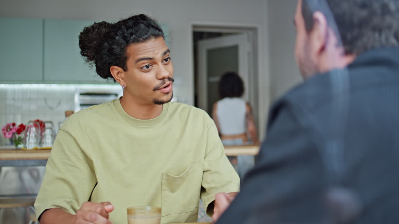 Two male friends talking in cafe close up. Multiracial men speaking together