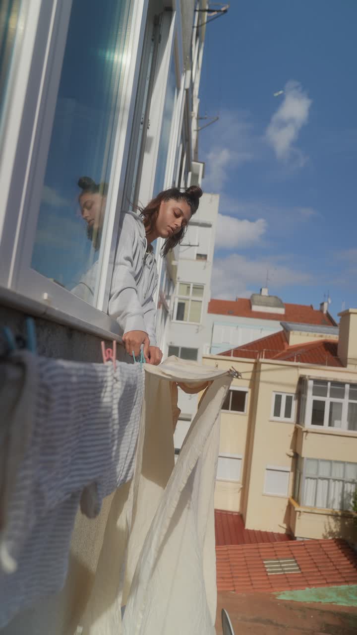 Woman Drying Clothes on Balcony
