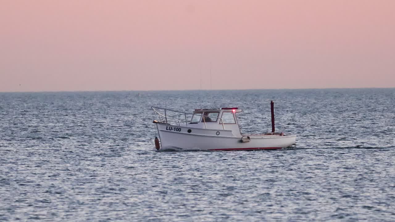 해가 지는 동안 평온한 바다에서 떠다니는 배