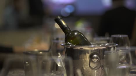 Chilled-wine-bottle-on-ice,-hand-grabbing-a-glass-at-an-elegant-business-event