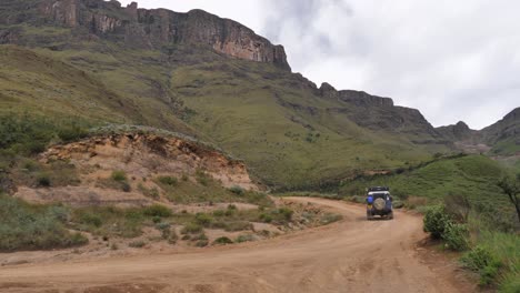 rugged land rover drives up rough gravel road of sani pass, s africa