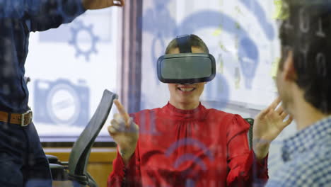 multiple blue digital icons floating against caucasian businesswoman wearing vr headset at office