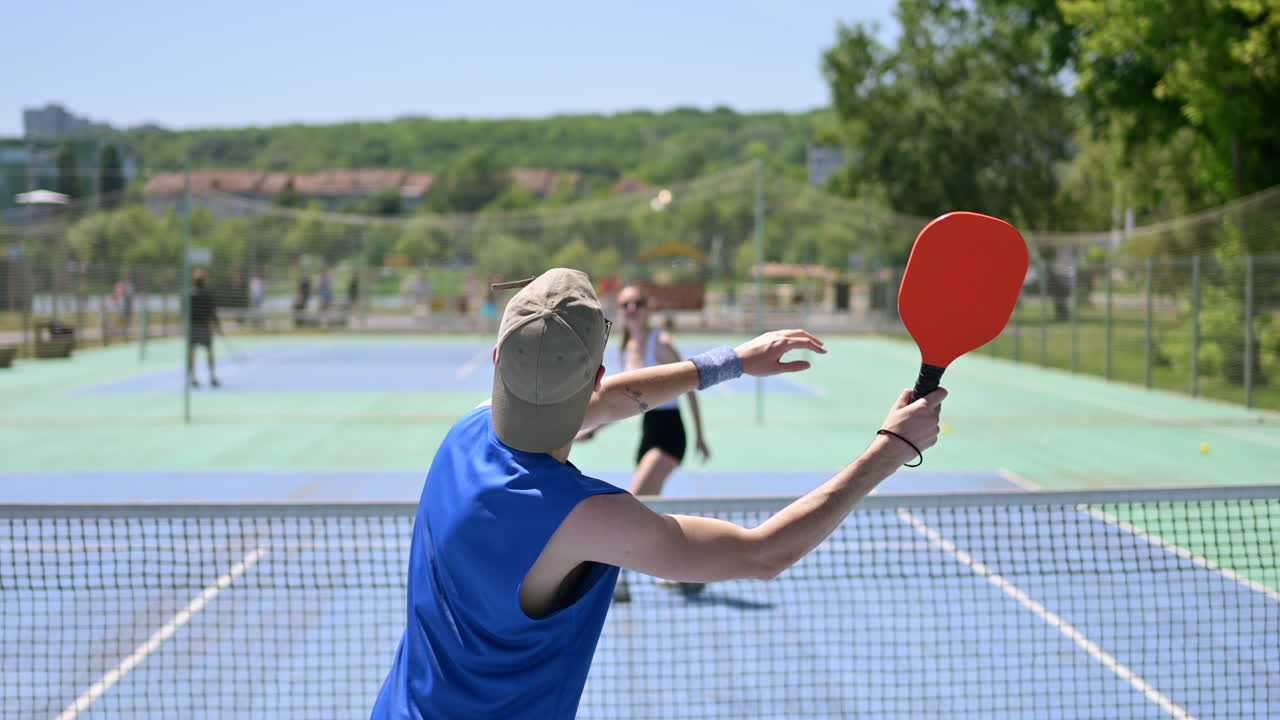 A man and a woman playing pickleball on a sunny day