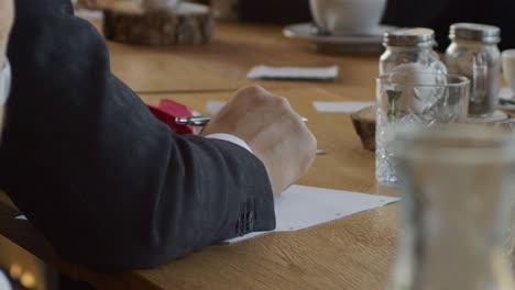 a young man in a business suit takes notes during a business meeting