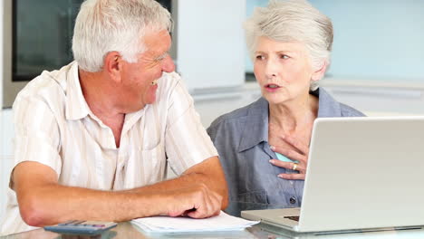 senior couple using laptop to pay their bills