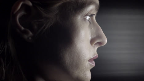 perfil lateral de una cara femenina mirando fijamente a un eje de luz en un estudio con fondo negro