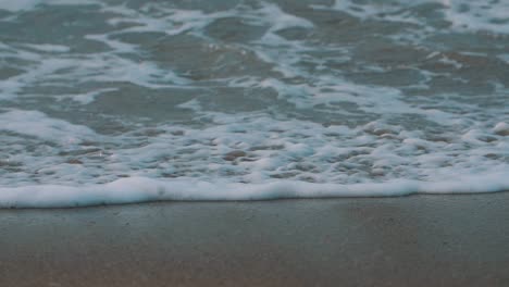 close-up shot of the foam of the waves crashing on the sand, the shore of the beach in colombia
