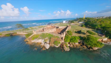 fpv drone flight over san felipe fortress and harbor with boats in puerto plata during sunny day