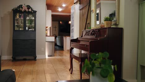 a panning shot of a wooden piano in the living room of a farmhouse