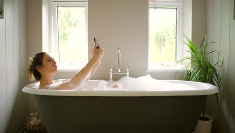 woman taking a selfie in a bubbly bath