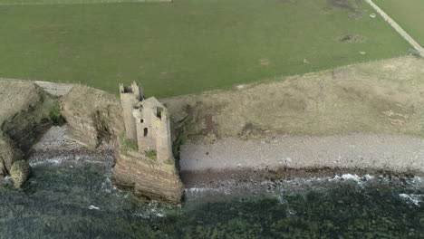 Aerial-shot-backing-away-from-above-Keiss-Castle-out-towards-the-sea-on-a-sunny-day,-Caithness,-Scotland