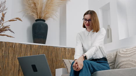 woman wearing glasses having video conversation via the laptop. working remote from home. low angle view.