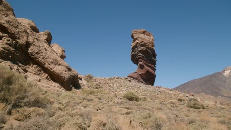 Pico-del-Teide-revealed-behind-eroded-volcanic-rocky-monument,-Los-Roques-de-Garcia,-Teide-National-Park-in-Tenerife,-Canary-Islands-in-spring