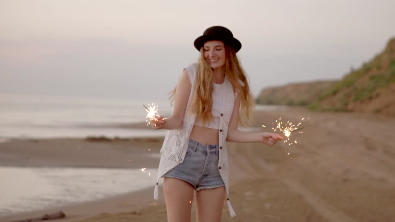Happy Woman with Sparkler on the Beach at Sunset