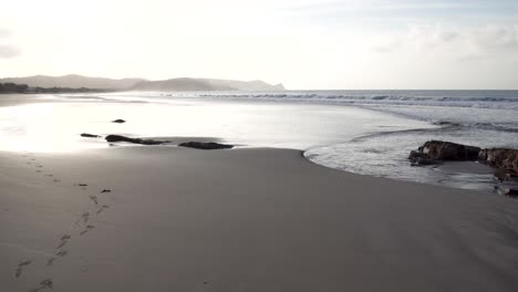 Rocky-area-of-Popoyo-Beach-Nicaragua-with-rocks-hit-by-waves-at-dusk,-Handheld-wide-shot