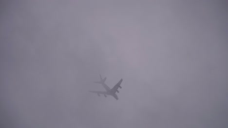 Low-angle-shot-of-the-airplane-flying-in-the-sky-on-a-foggy-cloudy-autumn-day,-tracking-shot