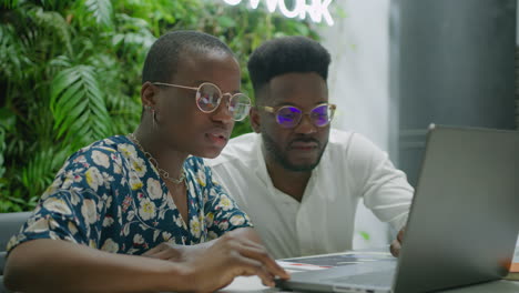 african american colleagues using laptop in coworking room
