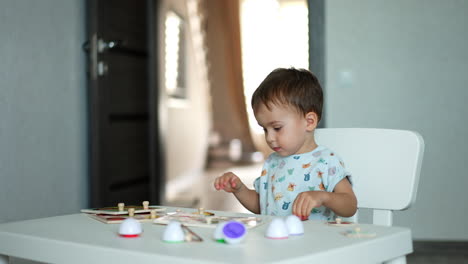 adorable cute toddler playing with toys at home. lovely child collecting puzzles at the desk.