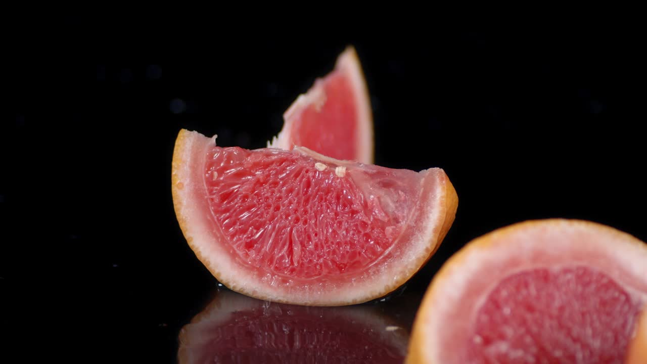 los pedazos de toronja caen sobre las salpicaduras de agua.
