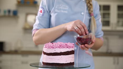 woman decorating a pink layer cake