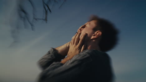 man with hands on face looking up at the sky