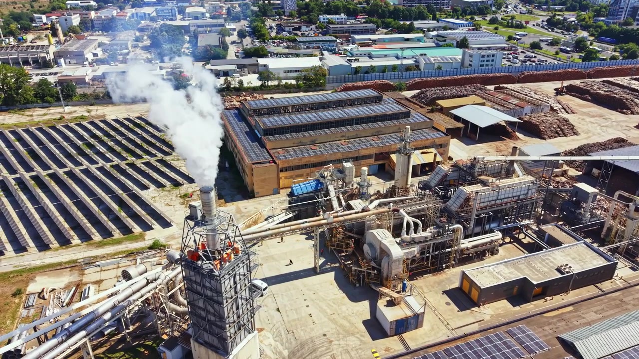 Gündüz, duman ve binaların olduğu bir sanayi bölgesinde fabrika faaliyeti.