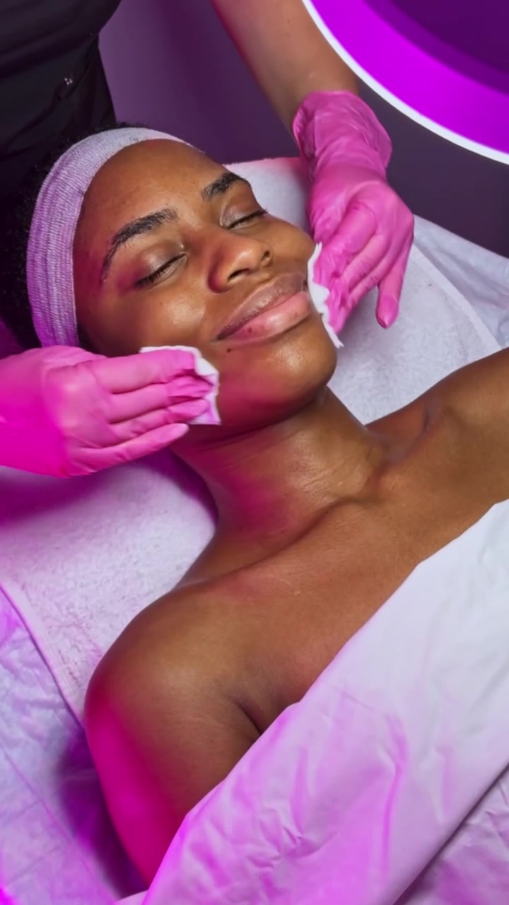 Une femme reçoit un soin du visage dans un salon de beauté en journée, axé sur la relaxation et les soins de la peau