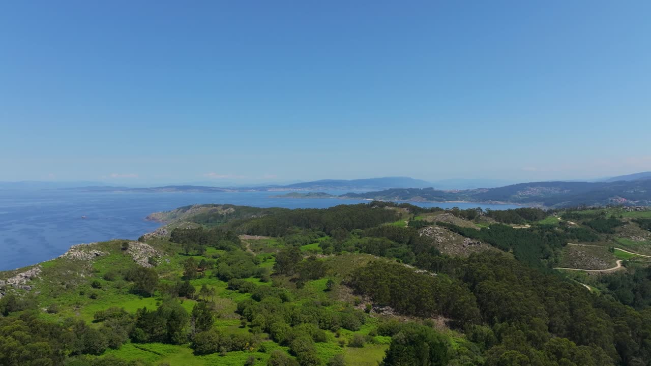 vista aérea de bosque verde y montaña con el mar azul en un día soleado en españa
