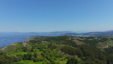 Aerial-View-Of-Green-Forest-And-Mountain-With-The-Blue-Sea-On-A-Sunny-Day-In-Spain