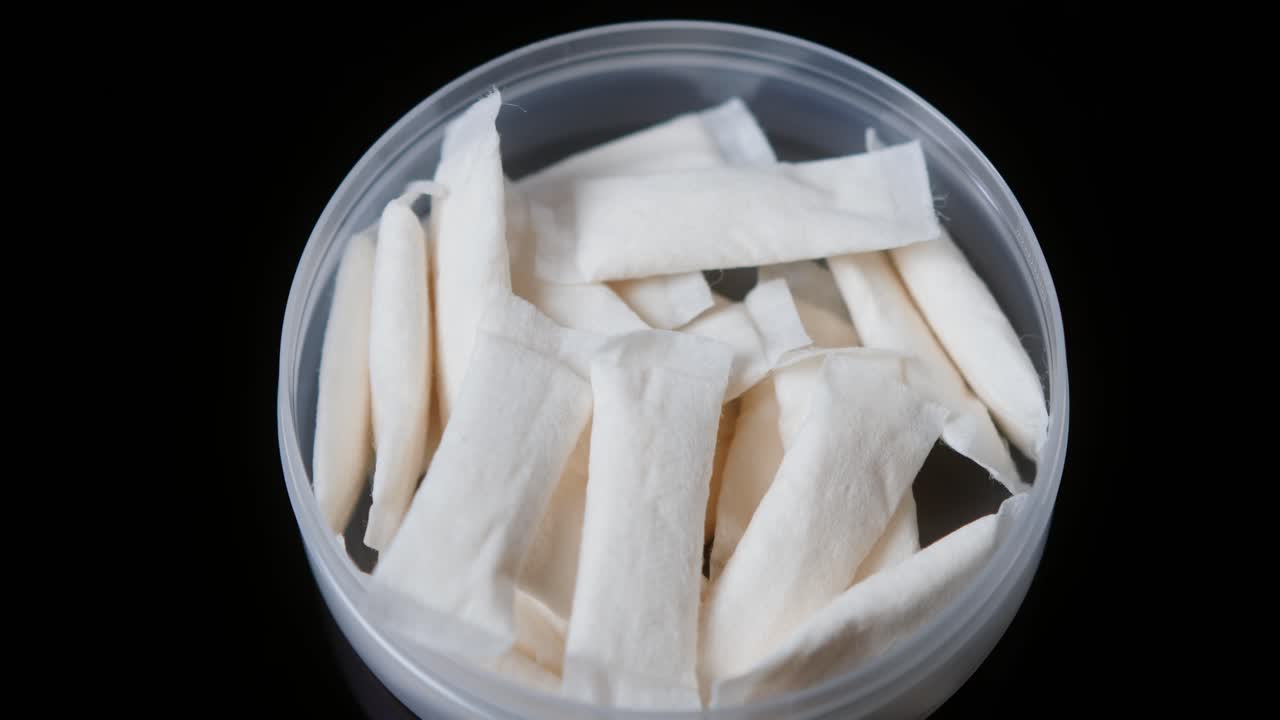 Snus nicotine tobacco close up, pack of tobacco for gum. unhealthy addiction. Man opening box with snus and taking one.