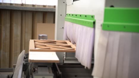 a large white and green machine cuts out a design on wood