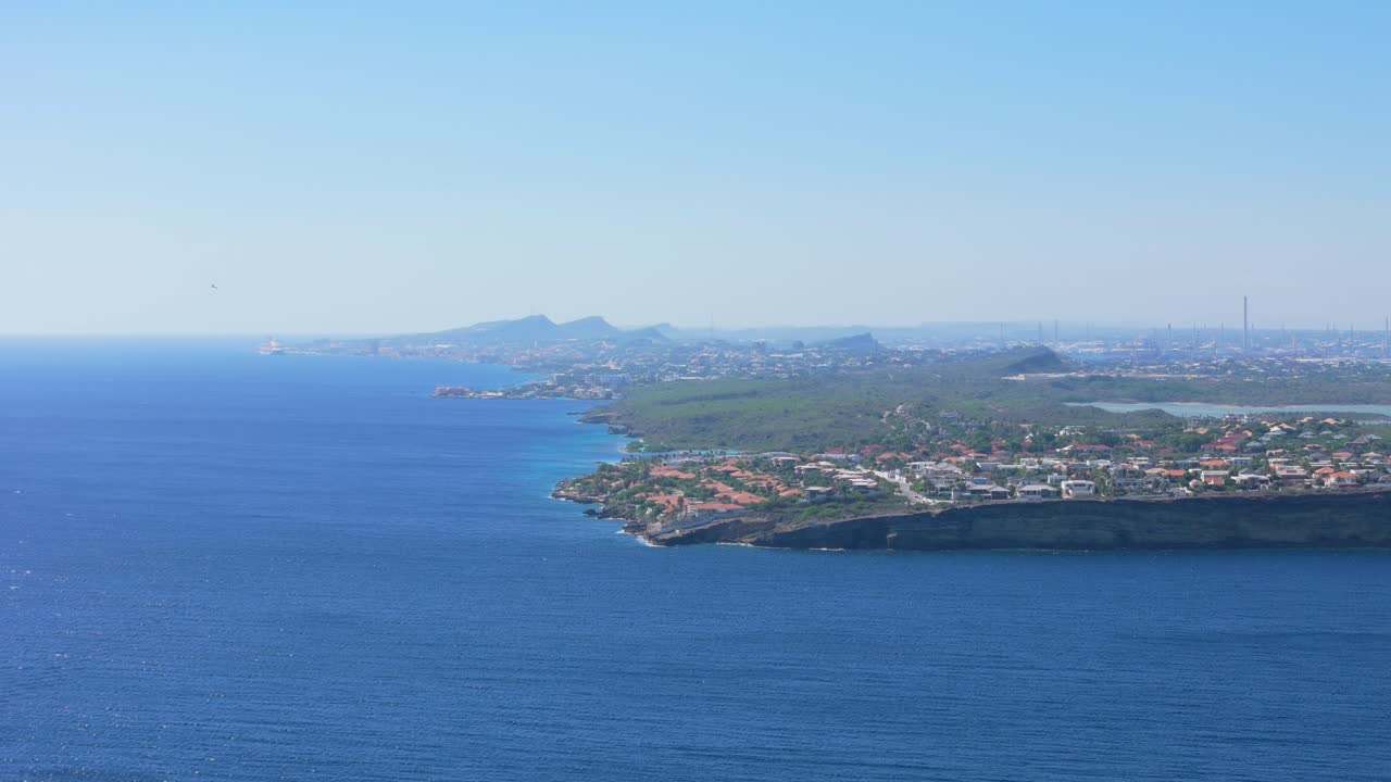 Aerial orbit of frigate birds gliding through the open skies along the coastline of Curacao, set against a stunning backdrop of the ocean and horizon