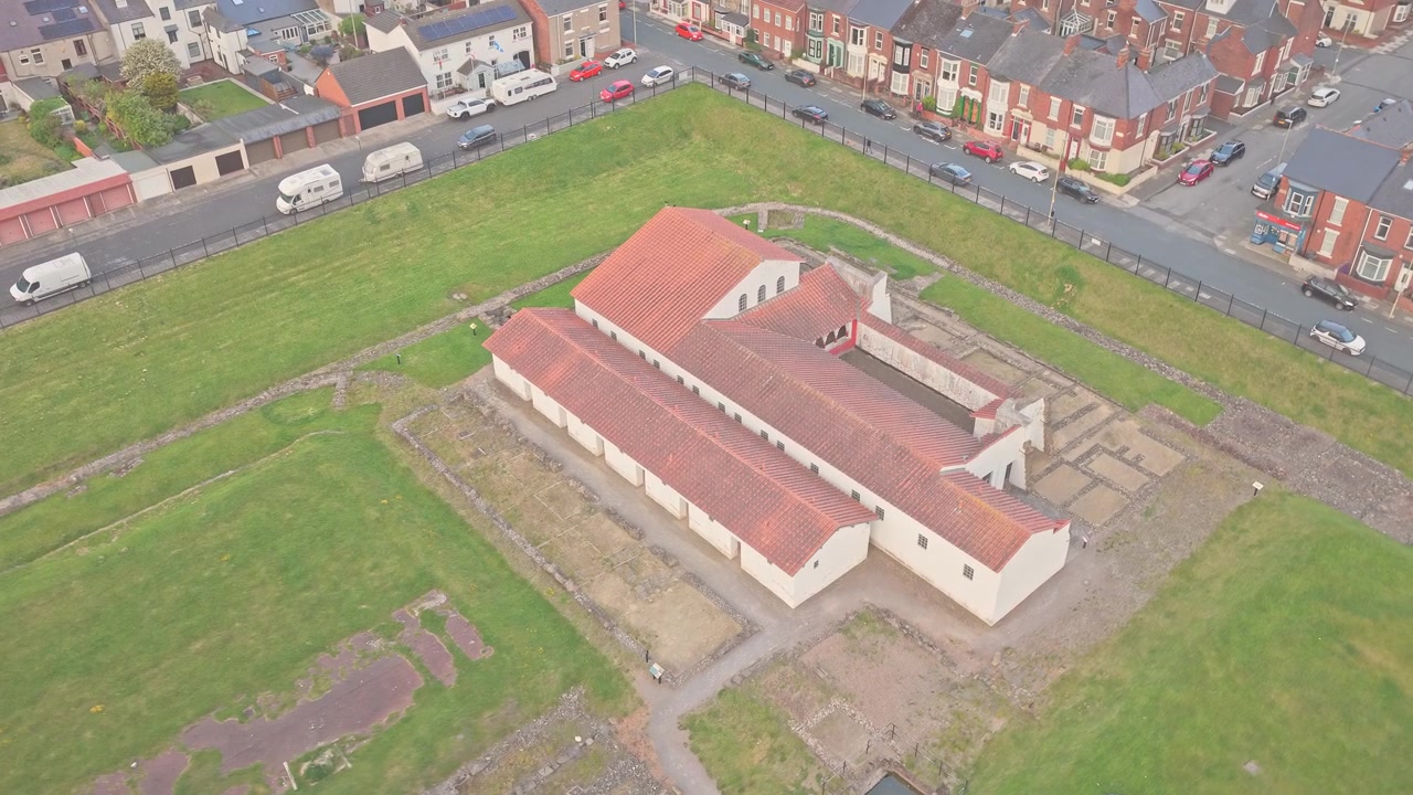 Drone flyr fremover over det rekonstruerte porthuset til Arbeia romerske fort i South Shields, South Tyneside, Tyne and Wear, England, som avslører romerske arkeologiske rester og forsvarsfundamenter