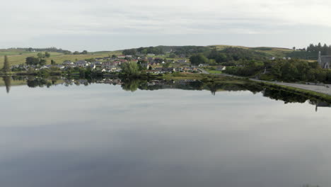 Eine-Luftaufnahme-Des-Dorfes-Lairg,-Das-Sich-An-Einem-Ruhigen-Sommermorgen-Im-Flussschien-Spiegelt