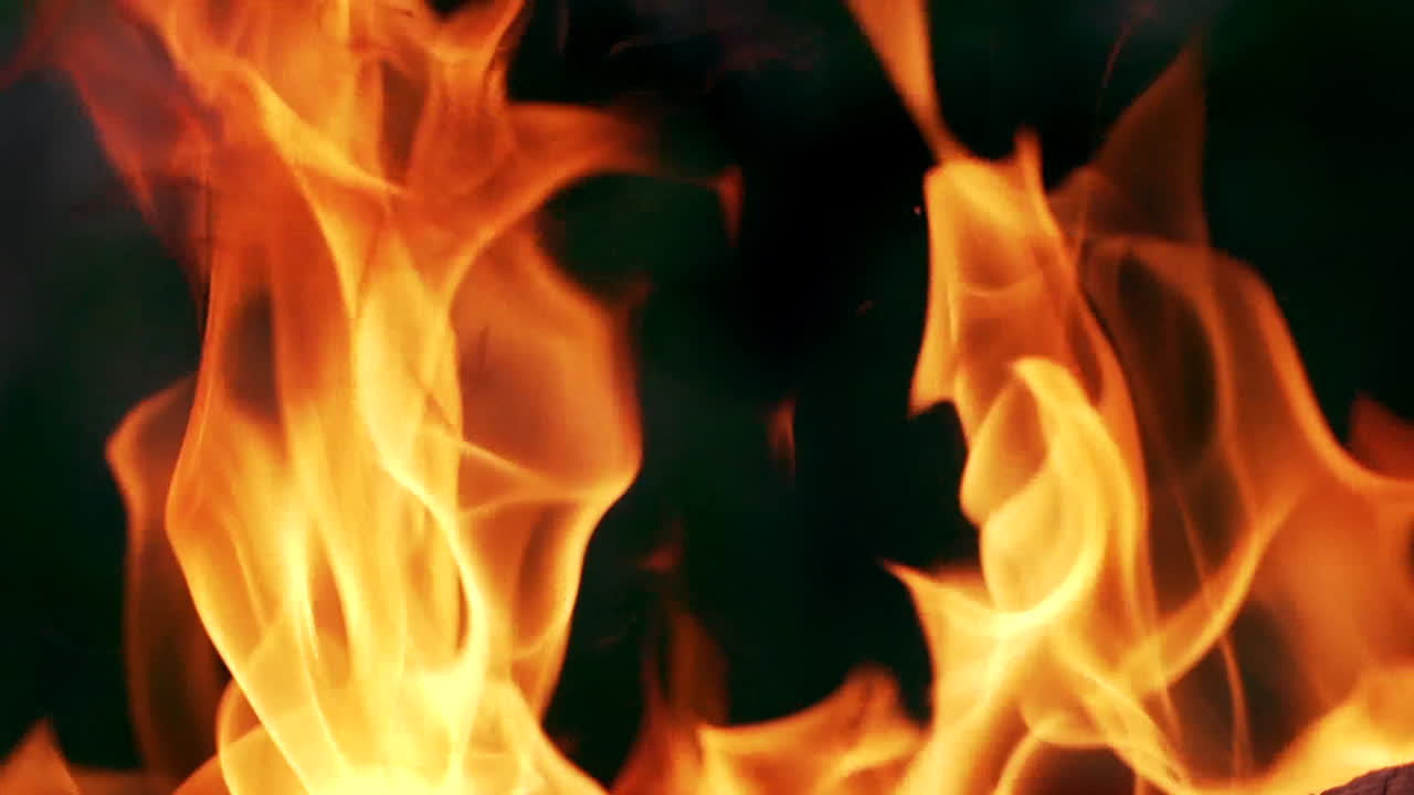 Dancing of beautiful orange flame at night. Close-up. Bright flame of fire on the dark background.