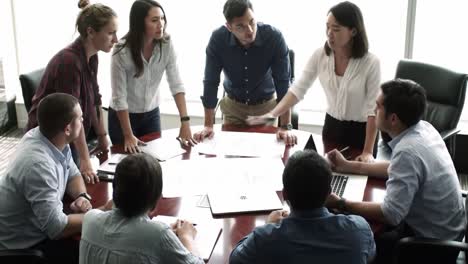 collaborative team meeting in a conference room: engaged participants discussing project plans and analyzing documents around a conference table
