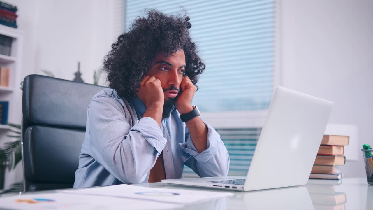 Disappoint arabian businessman looking at computer screen sitting at home office